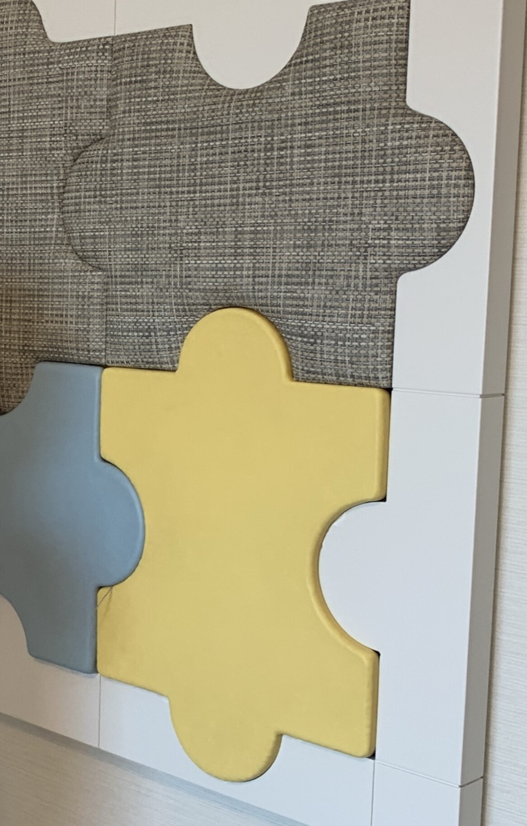 Close-up of a removable puzzle-piece wall panel, popped slightly out from the wall