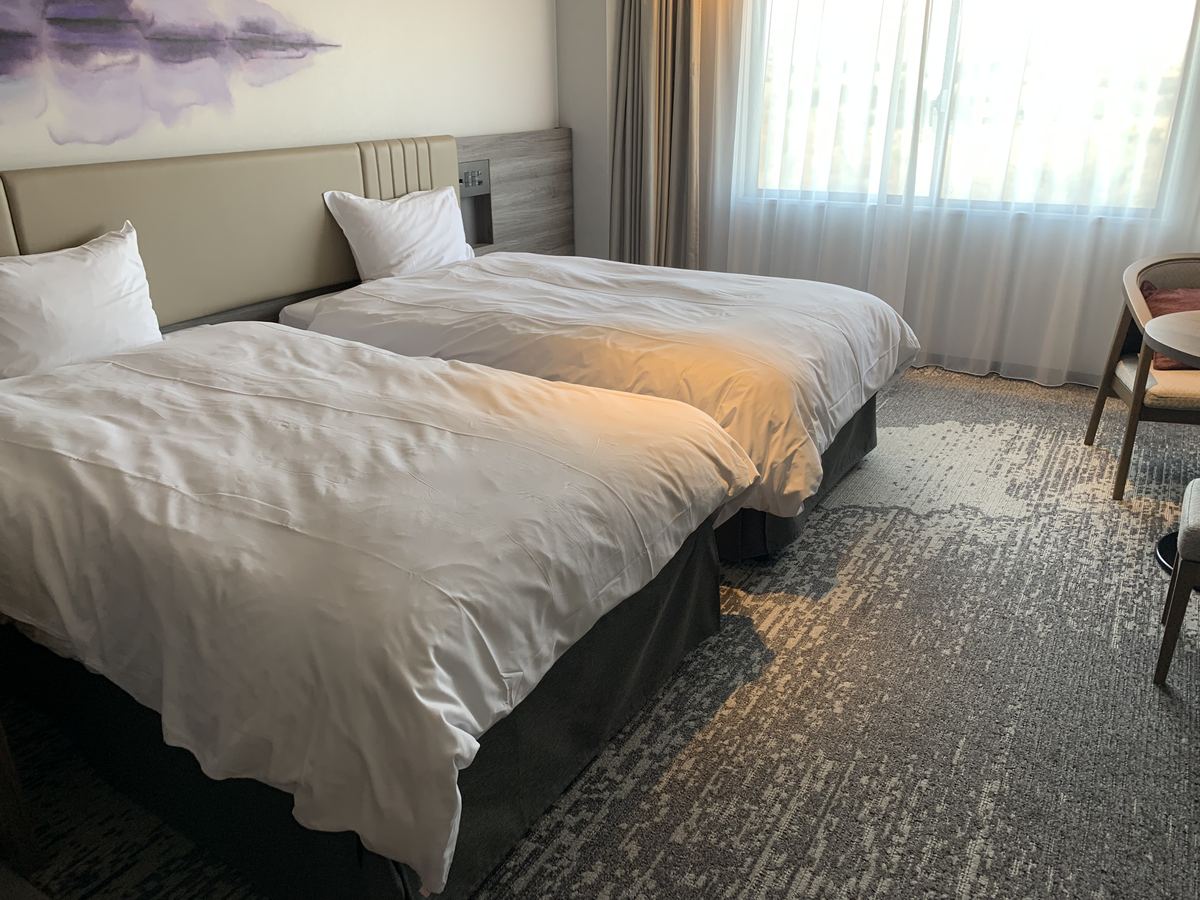The Superior Twin room at Grand Mercure Nasu Highlands, with two beds, a large window, and a chair