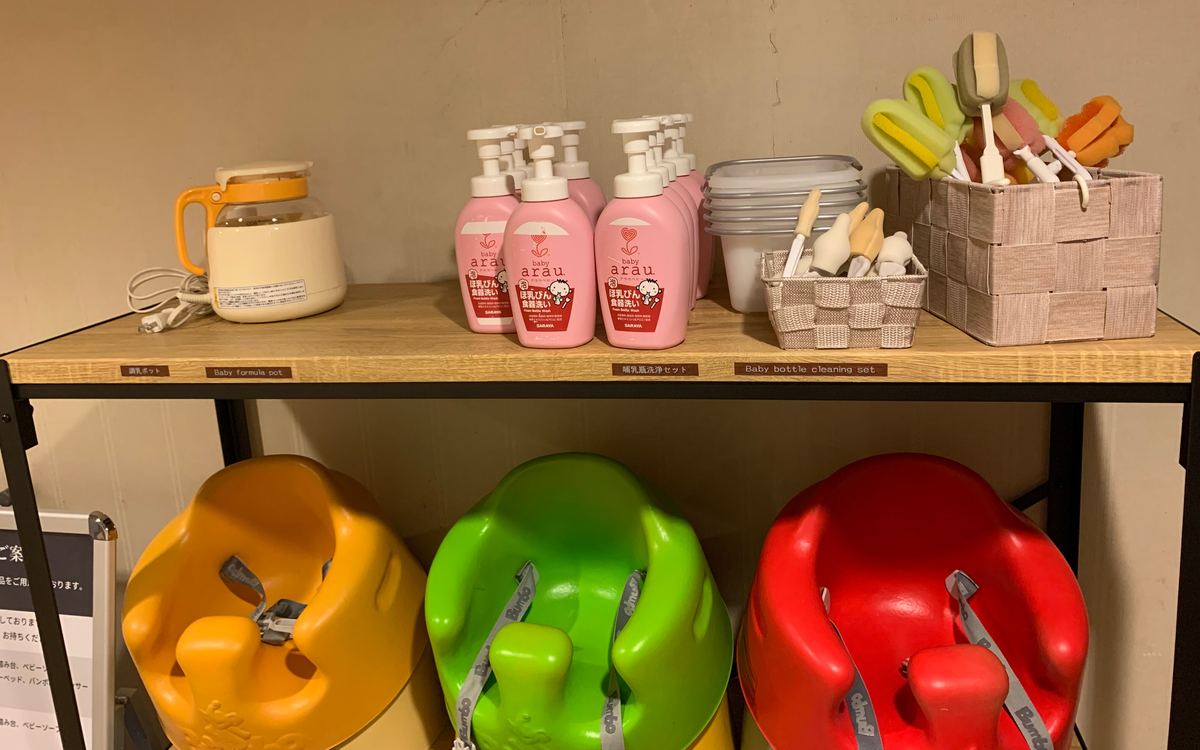 The loanable baby-gear shelf at Grand Mercure Nasu Highlands, with a bottle-warming pot, baby bottle wash, cleaning brushes, and Bumbo floor seats, labeled in Japanese and English