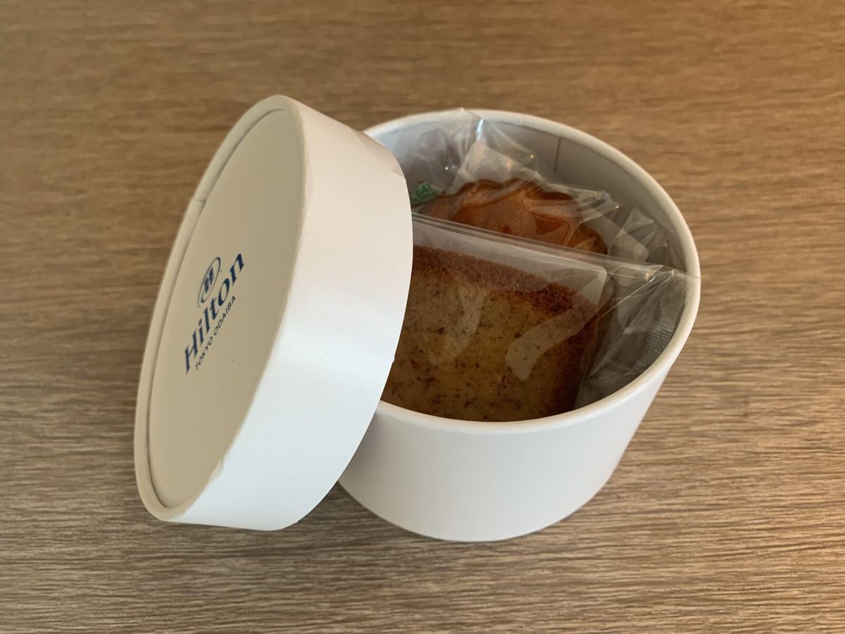 A round Hilton-branded box of financier pastries waiting in the room