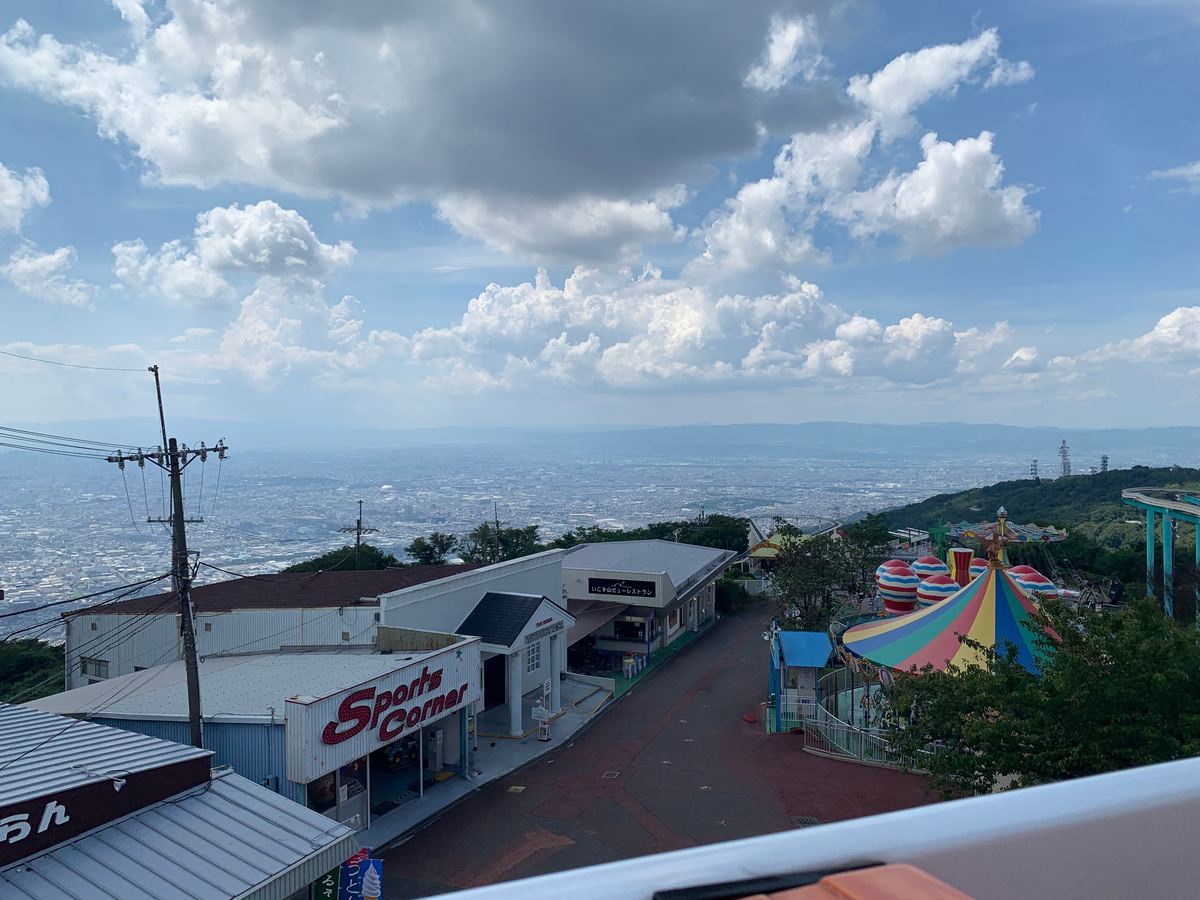 The park midway with kiddie rides in the foreground and the Osaka Plain spread out below