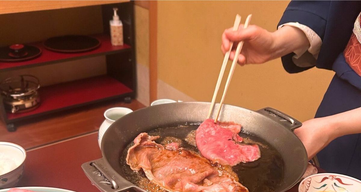 A server cooking the sukiyaki at the table in the private room