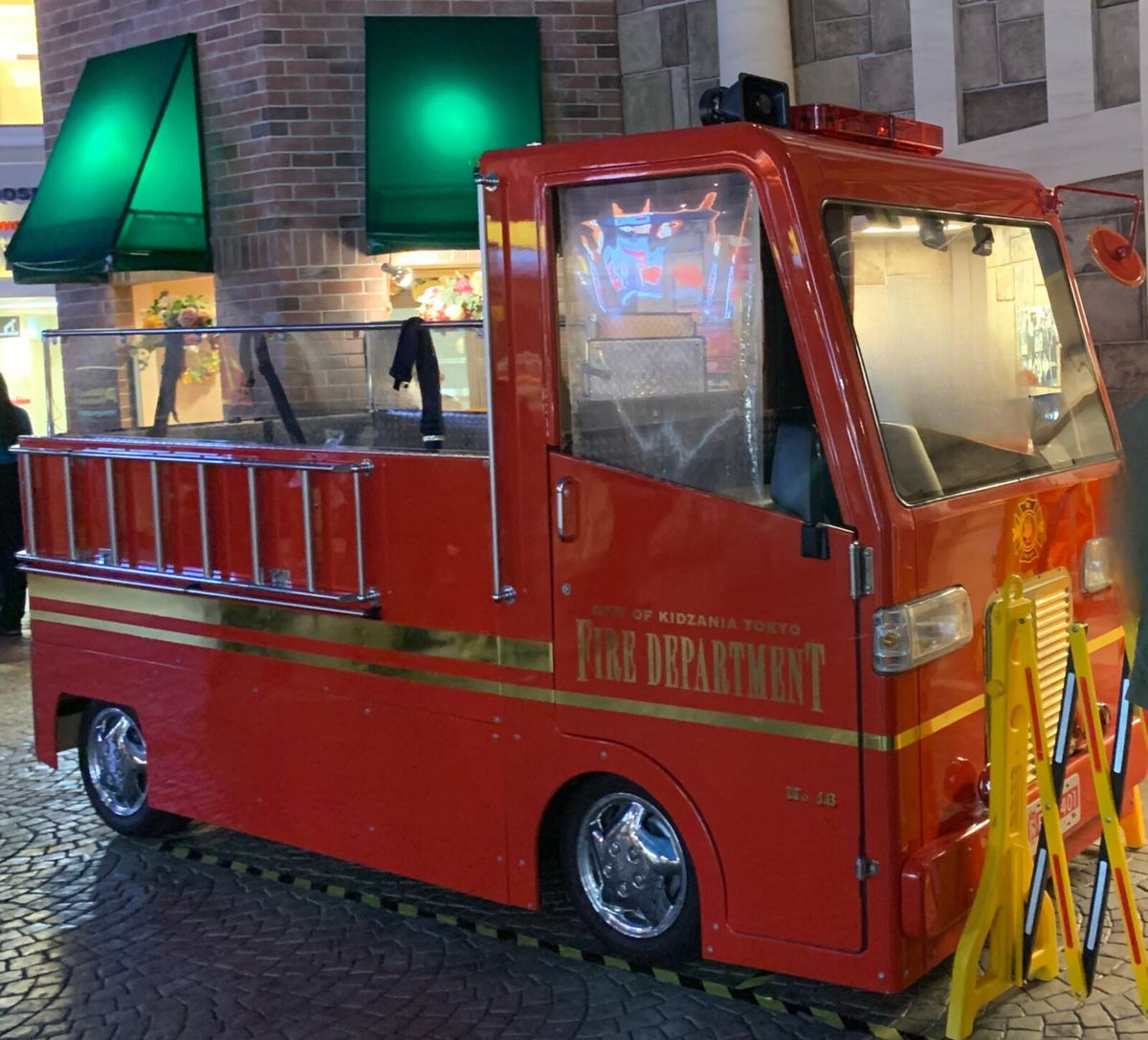 The kid-sized KidZania Tokyo fire truck parked outside the fire station