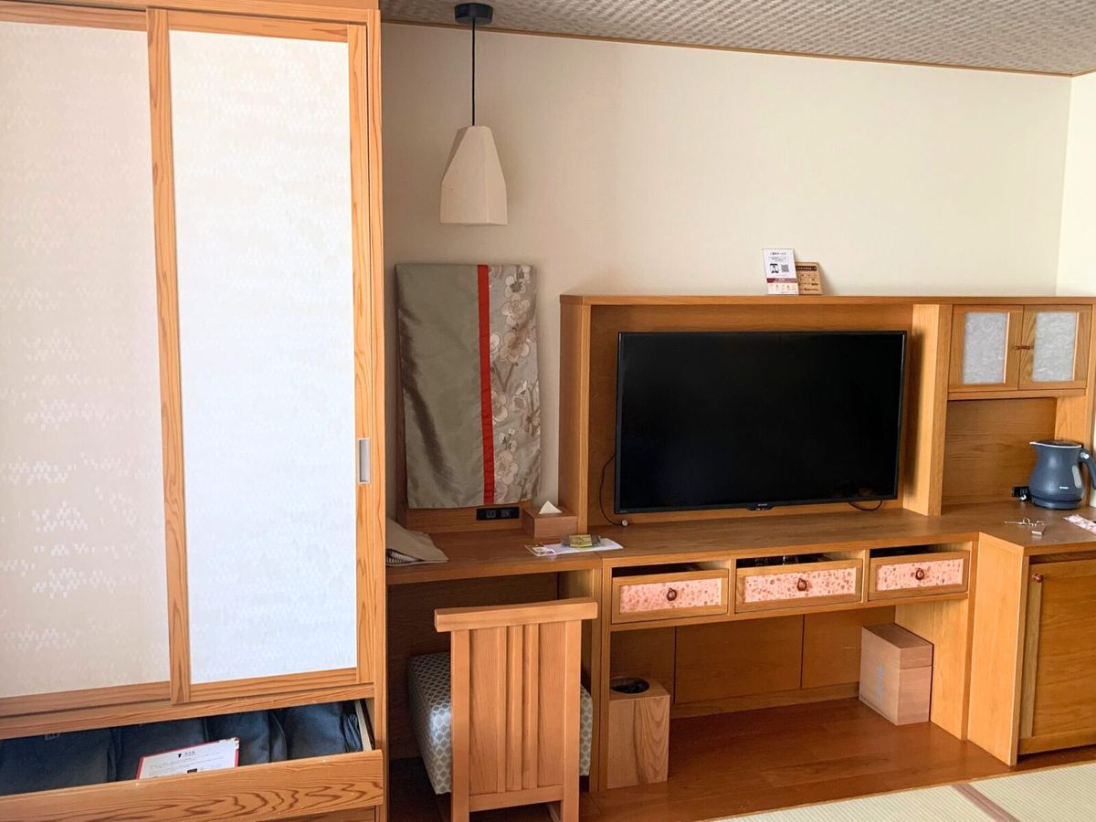 The room's TV corner with wooden cabinetry and shoji paper screens