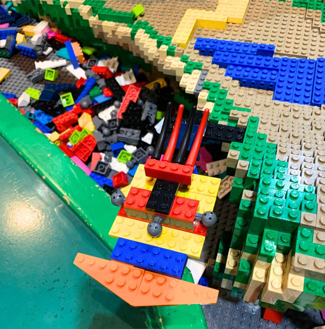 A close-up of the shared building table, half-finished creations mixed into the loose bricks
