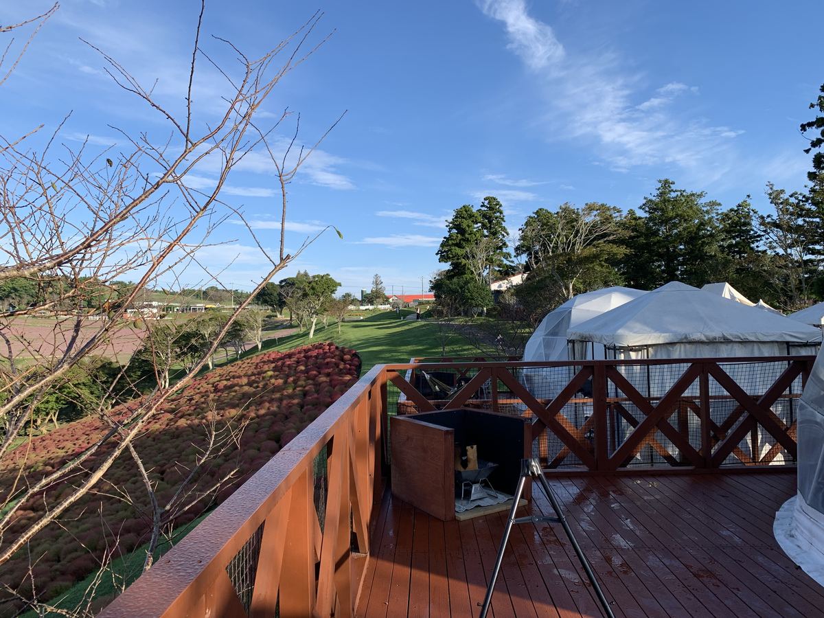 A glamping dome tent with a private wooden terrace, fire pit, and hammock overlooking the kochia-covered hillside at Mother Farm