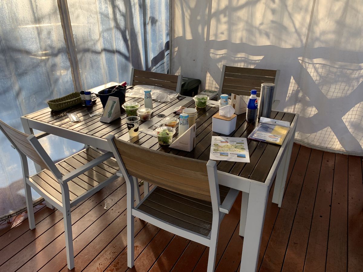 A set meal laid out on the table in the covered outdoor dining area — fresh salads, drinks, and a park map