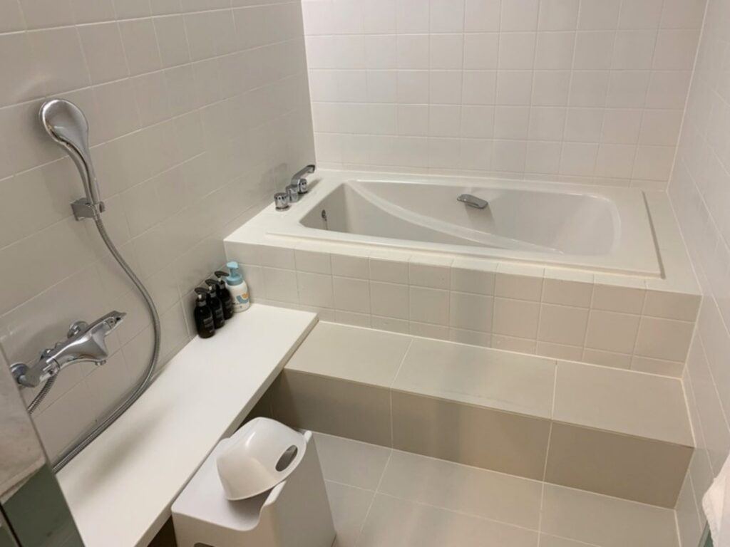 The white-tiled bathroom in our room, with a bathtub on a raised step