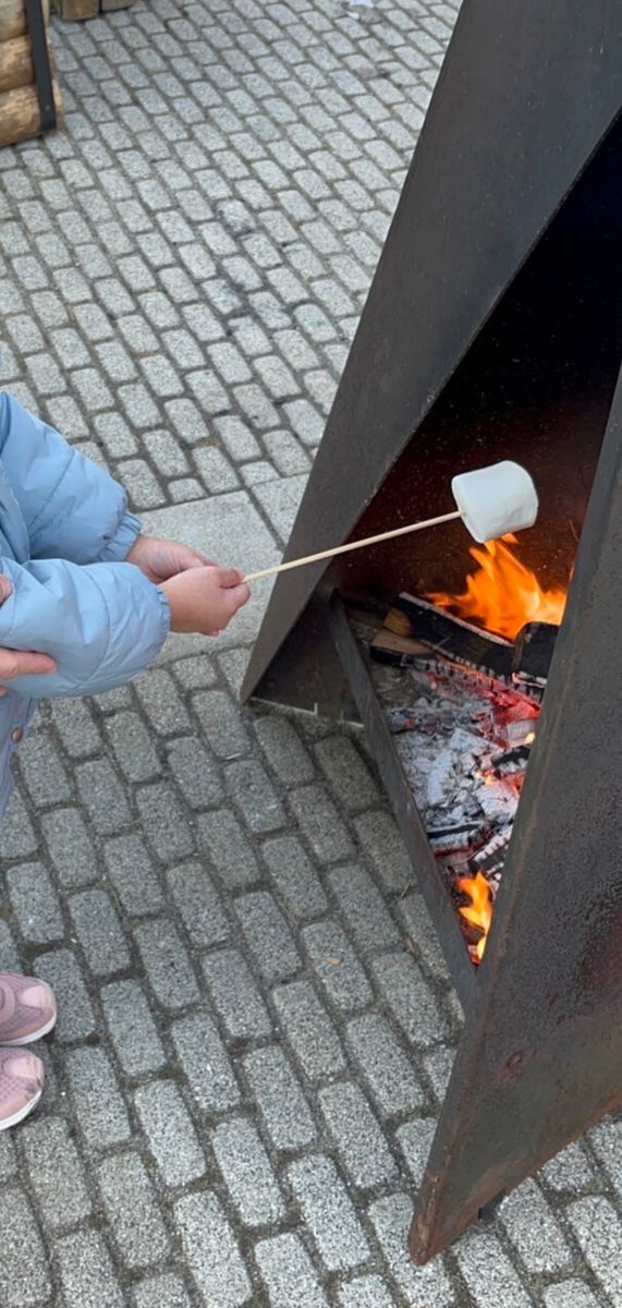 A child's hand roasting a marshmallow on a stick over the resort's fire pit
