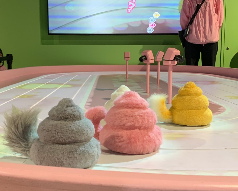 Fluffy poop-animal racers with tails lined up on the derby track