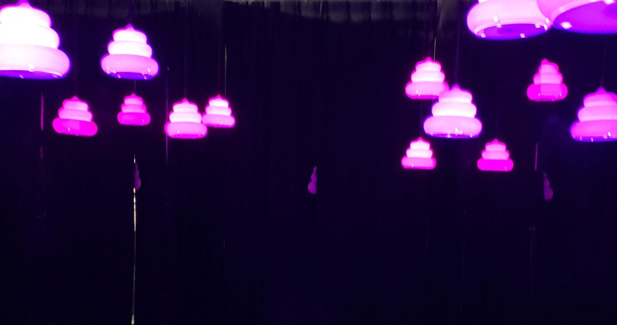 Glowing purple and pink poop shapes hanging in a dark room like a starfield